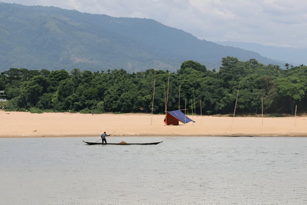 A sailor with his boat at Jadukata River, with mountains in the back,