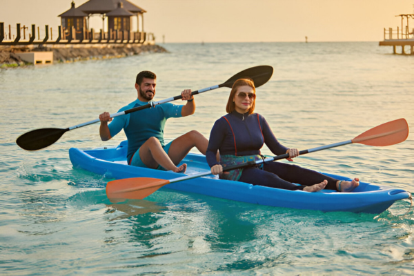 A tourist couple in Saudi Arabia kayaking in wetsuit.